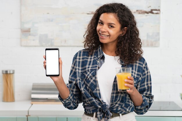 Linda mulher segurando um copo de suco e um telefone simulado