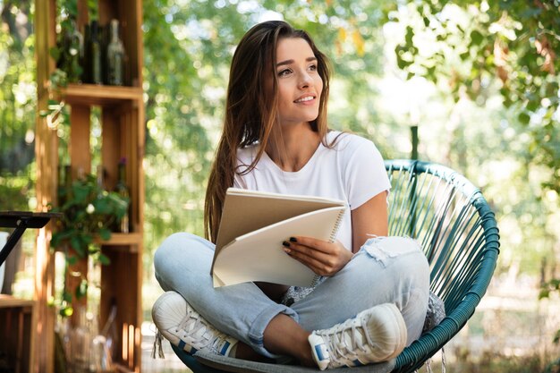 Linda mulher segurando um livro enquanto está sentado em uma cadeira