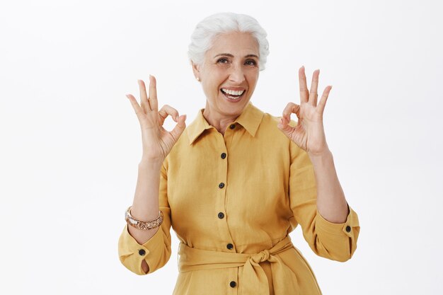 Linda mulher sênior sorridente mostrando gesto de aprovação, aprovo e gosto da ideia, serviço de garantia