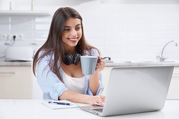 Linda mulher tomando café e estudando no laptop