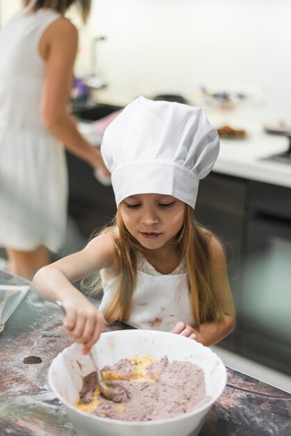 Linda pequena chef mistura pó de cacau e manteiga com colher