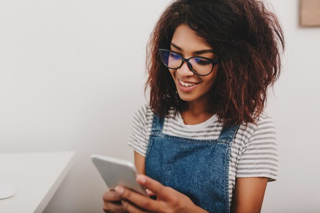 Linda senhora com pele bronzeada conferindo novas mensagens nas redes sociais pelo celular