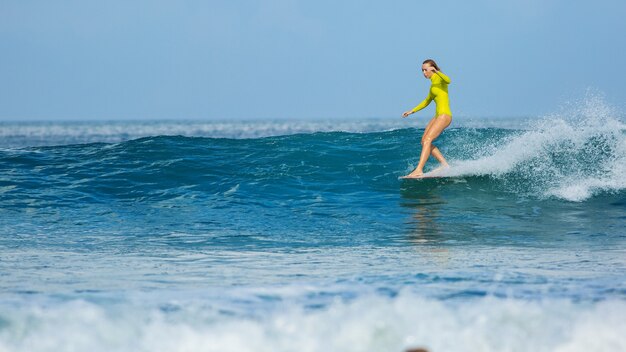 Linda surfista monta um longboard e faz um truque de passeio de nariz.