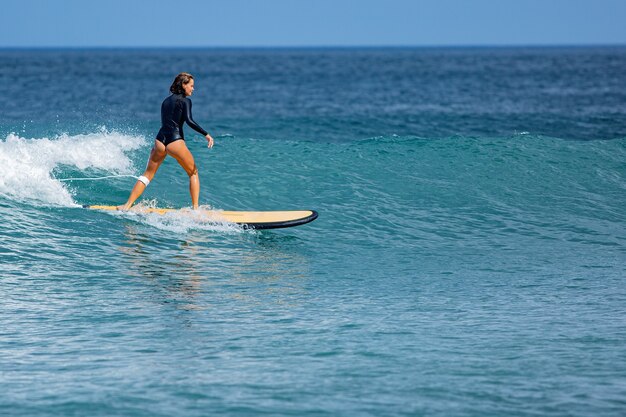 Linda surfista monta uma prancha de surf.