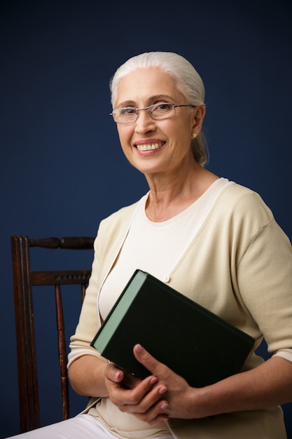 Linda velha alegre segurando o livro.