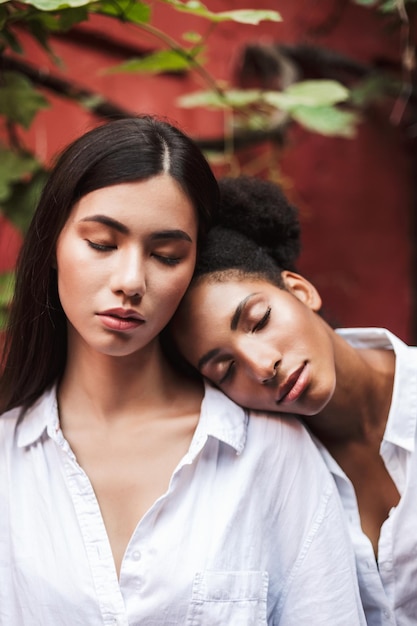 Foto grátis lindas garotas em camisas brancas sonhadoramente fechando os olhos inclinando as cabeças umas para as outras isoladas