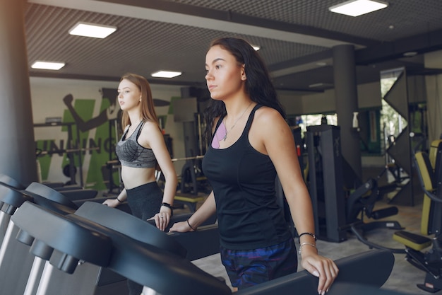 Lindas garotas em uma academia. mulheres do esporte em roupas esportivas. amigos em uma pista de corrida.