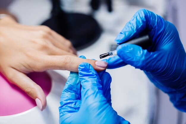 Lindas mãos femininas Processo de fabricação de tratamento de unhas de dedo Broca de lima de unha profissional em ação Conceito de beleza e cuidados com as mãos