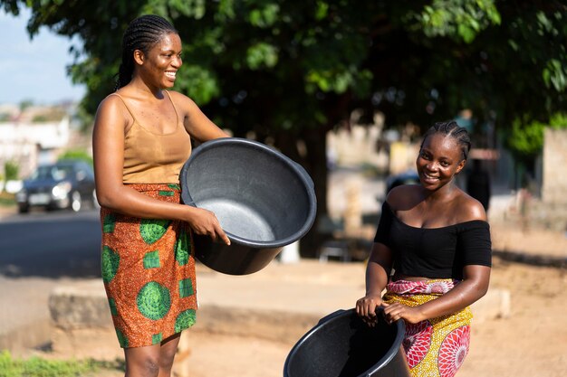 Lindas mulheres africanas se divertindo enquanto buscam água