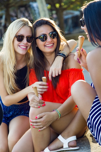 Lindas mulheres jovens se divertem com sorvete no parque.