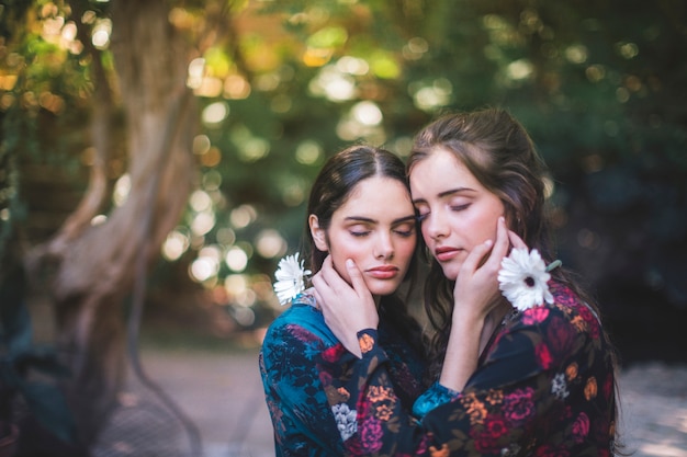 Lindas mulheres segurando flores e abraçando com os olhos fechados