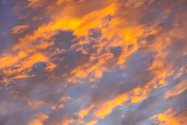 Lindas nuvens fofas alaranjadas abstratas no céu do nascer do sol - fundo colorido da textura do céu da natureza