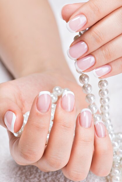 Lindas unhas de mulher com linda manicure francesa e pérolas brancas