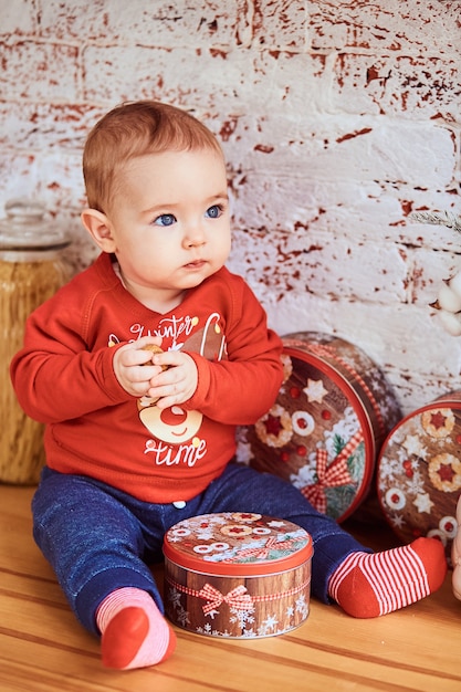Foto grátis lindo bebê sentado à mesa segurando uma noz e olhando para o lado