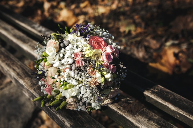 Lindo buquê de noiva deitado em um banco do parque, casamento no outono