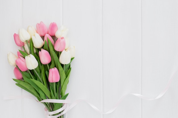 Lindo buquê de tulipas cor de rosa e brancas em fundo branco de madeira