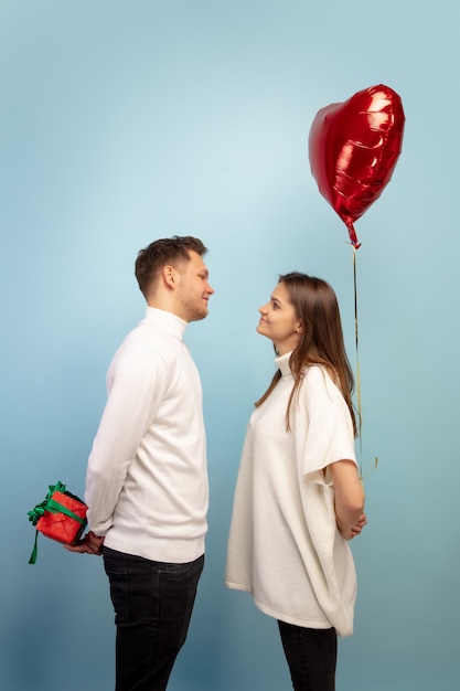 Foto grátis lindo casal apaixonado por um balão em forma de coração na parede azul do estúdio