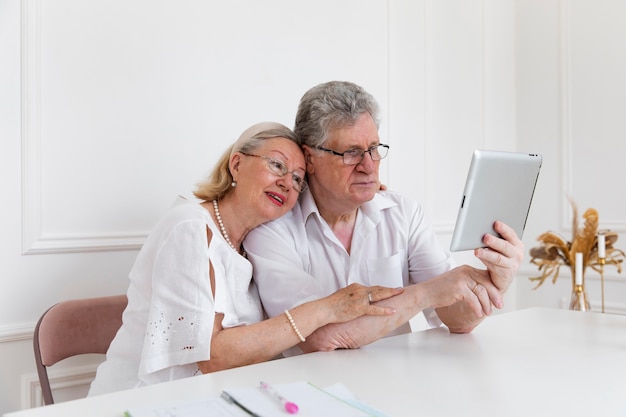 Lindo casal de avós aprendendo a usar um dispositivo digital
