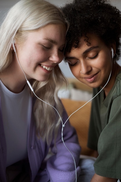 Lindo casal de lésbicas ouvindo música nos fones de ouvido