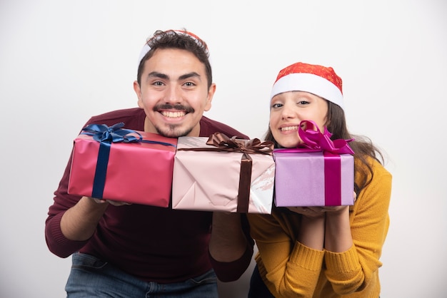 Lindo casal de natal segurando presentes em um fundo branco.