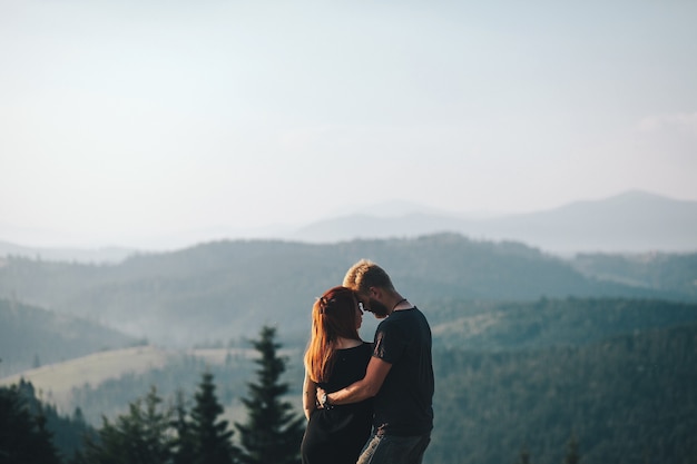 Lindo casal em pé em uma montanha olhando um para o outro
