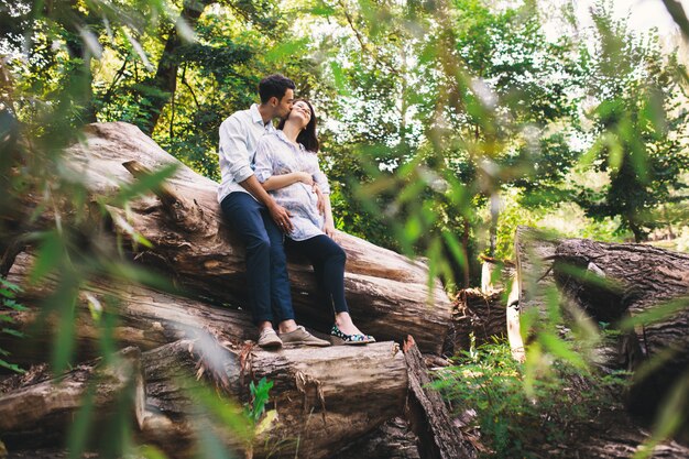 Lindo casal grávida relaxante lá fora na floresta