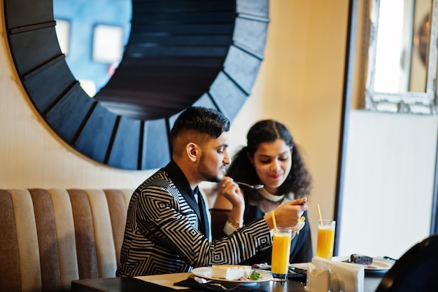 Lindo casal indiano apaixonado usa saree e terno elegante sentado no restaurante e comendo sorvete juntos