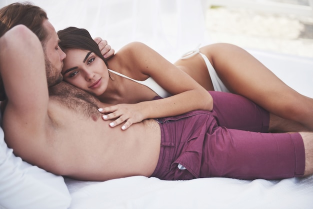 Lindo casal jovem em trajes de banho na praia contra um sorriso de areia e abraço.