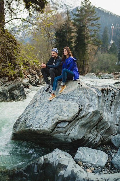 Lindo casal jovem hippie apaixonado caminhando sobre uma pedra no rio na floresta de inverno