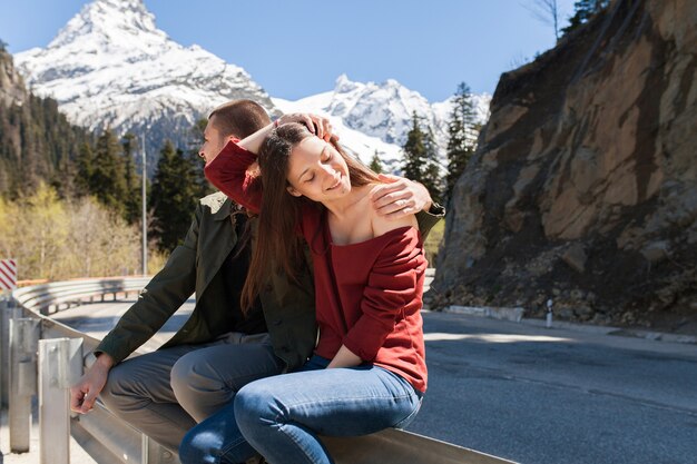 Lindo casal jovem hippie apaixonado, sentado na estrada