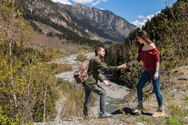 Lindo casal jovem hippie caminhando em um rio na floresta