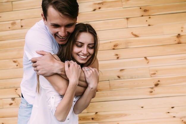 Lindo casal jovem posando em uma parede de madeira