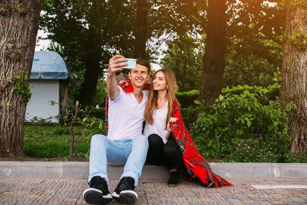 Lindo casal jovem relaxando no parque e fazendo selfie