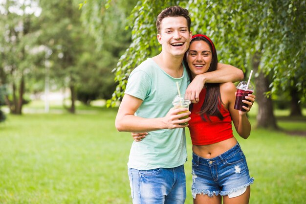 Lindo casal jovem segurando smoothies em copo de plástico