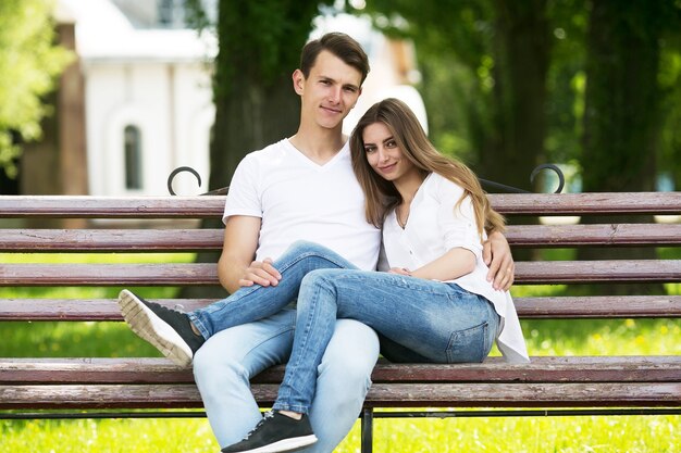 Lindo casal jovem sentado em um banco do parque