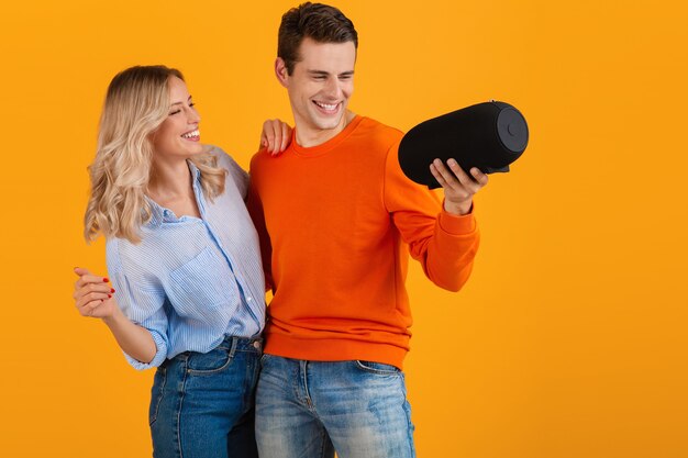 Lindo casal jovem sorridente segurando alto-falante sem fio e ouvindo música dançando emocional