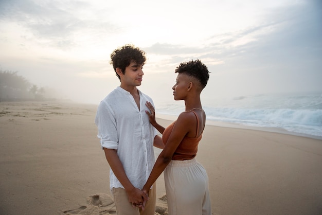 Lindo casal mostrando carinho na praia perto do mar