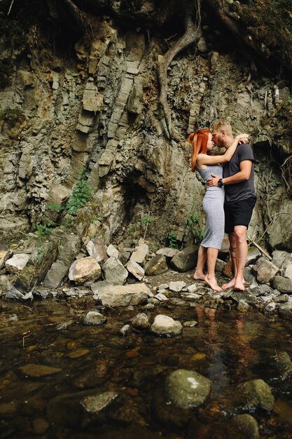 Lindo casal se abraçando perto de um rio na montanha