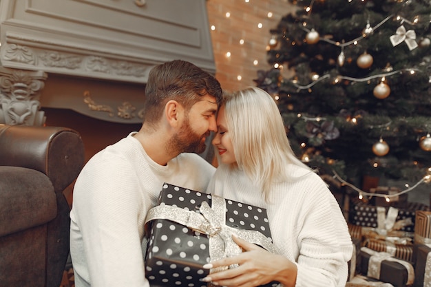 Lindo casal sentado em casa perto da árvore de natal