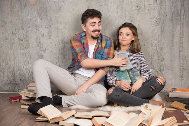 lindo casal sentado no chão com muitos livros