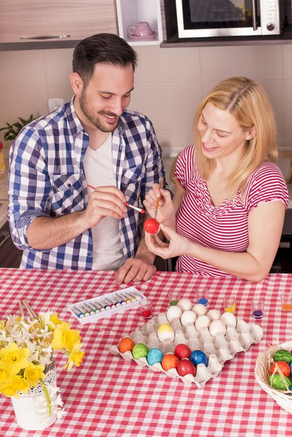 Foto grátis lindo casal sorrindo e pintando os ovos de páscoa