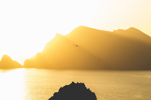 Lindo mar com montanhas ao fundo, sob um céu ensolarado