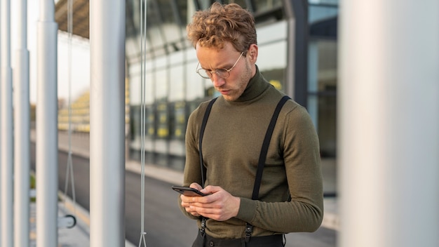 Lindo modelo masculino olhando para baixo em seu telefone