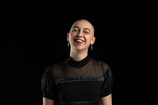 Língua de fora, caretas. Retrato monocromático de jovem careca caucasiana na parede preta. Linda modelo feminino. Emoções humanas, expressão facial, vendas, conceito de anúncio. Cultura jovem.