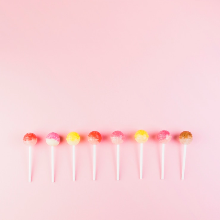 Foto grátis linha de pirulitos coloridos no fundo rosa