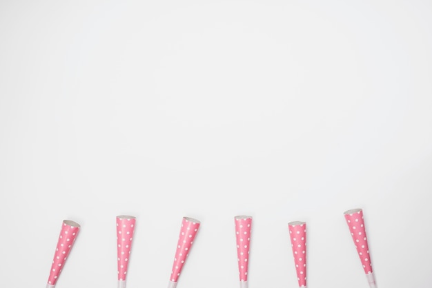 Foto grátis linha de ventiladores de chifre de festa-de-rosa sobre fundo branco