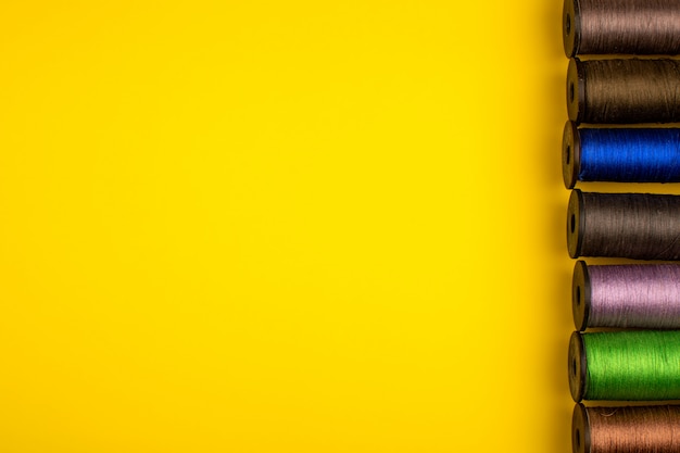 Foto grátis linhas de costura multicoloridas alinhadas em um fundo amarelo