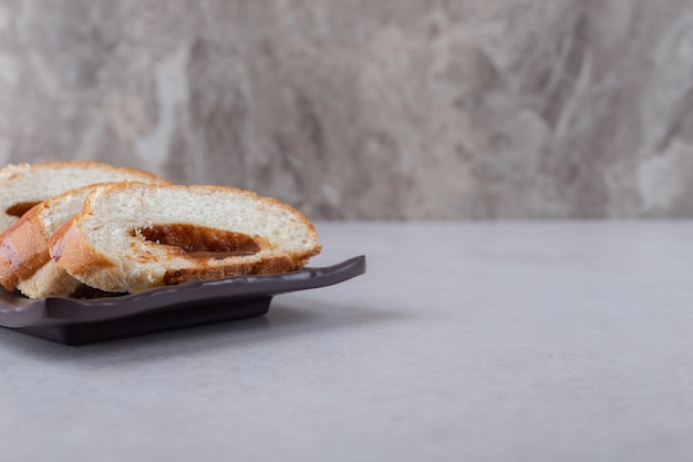 Linhas de pedaços de torta doce na placa de madeira, no mármore.