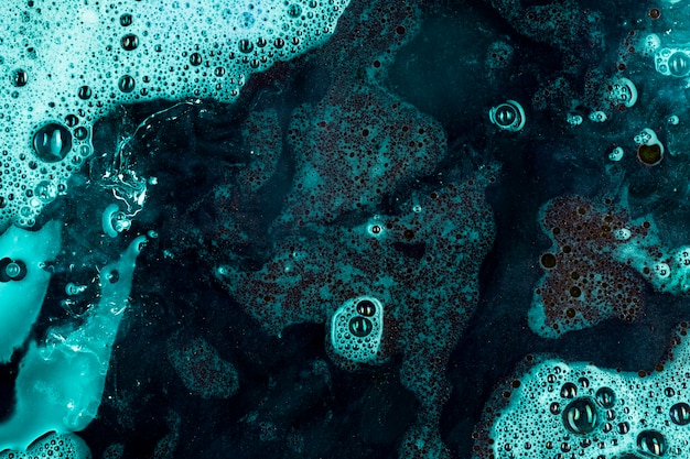 Líquido azul profundo com espuma e gotas pretas