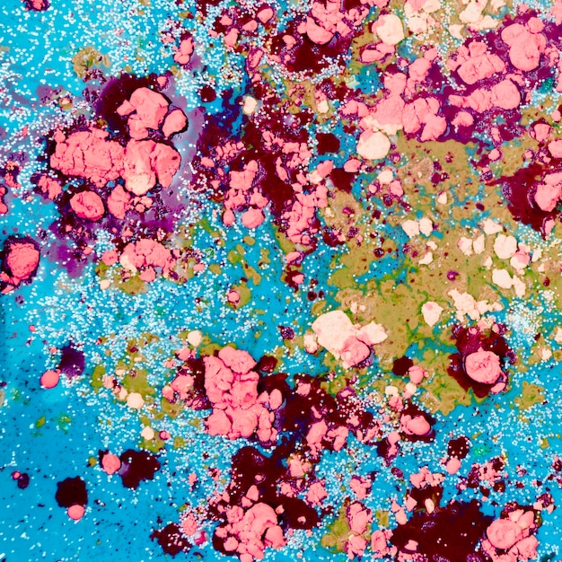 Líquido de água-marinha misturando-se com migalhas cor-de-rosa